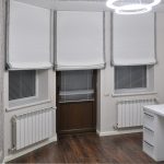 Римські штори світло-сірого кольору в сучасному кабінеті на трьох вікнах